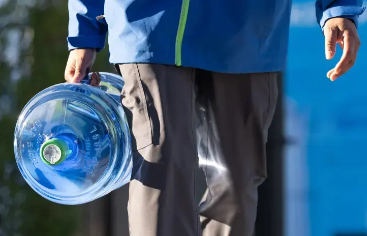 Person carrying water jug for delivery